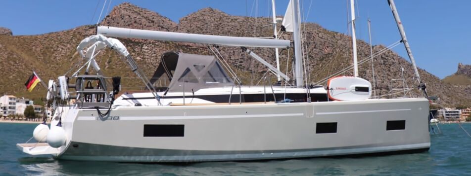 Seitenansicht der Segelyacht Bavaria C38 „Levante" mit grauem Rumpf und Bimini vor Anker in einer Bucht – Yachtcharter Mallorca