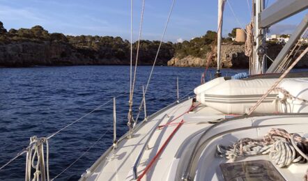 Vordeck der Segelyacht Bavaria cruiser 45 „Eva" mit verstautem Beiboot beim Anlaufen einer Felsküste – Yachtcharter Mallorca