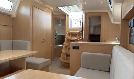 Salon der Segelyacht Bavaria C38 „Levante" mit Esstisch, Sitzgruppe und Niedergang, Türen zu den Kabinen – Yachtcharter Mallorca