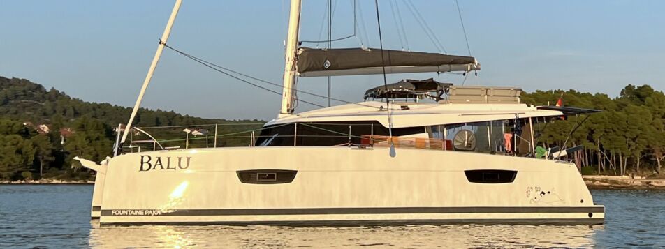 Seitenansicht des Katamarans Elba 45 „Balu“ vor Anker in einer bewaldeten Bucht bei Biograd – Yachtcharter Kroatien