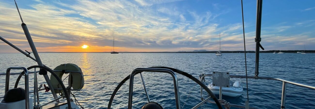 Sonnenuntergang über dem Wasser mit Blick vom Cockpit von einer Segelyacht auf Mallorca