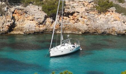 Segelyacht Bavaria cruiser 45 „Eva" vor Anker in einer türkisfarbenen Felsbucht mit Pinien auf Mallorca – Yachtcharter